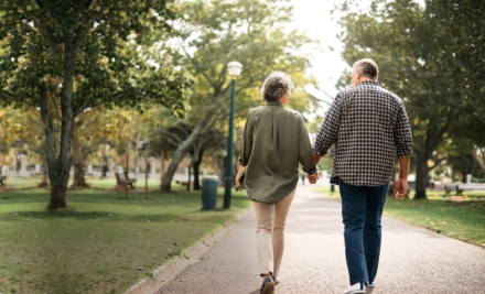A couple holding hands and walking in a park.