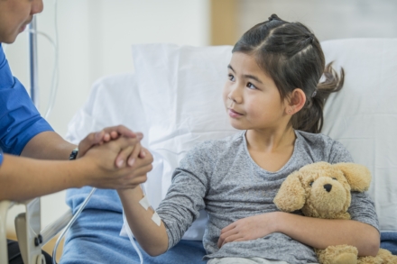 Child cancer patient comforted by adult in hospital