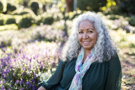 Woman smiling with flowers behind.