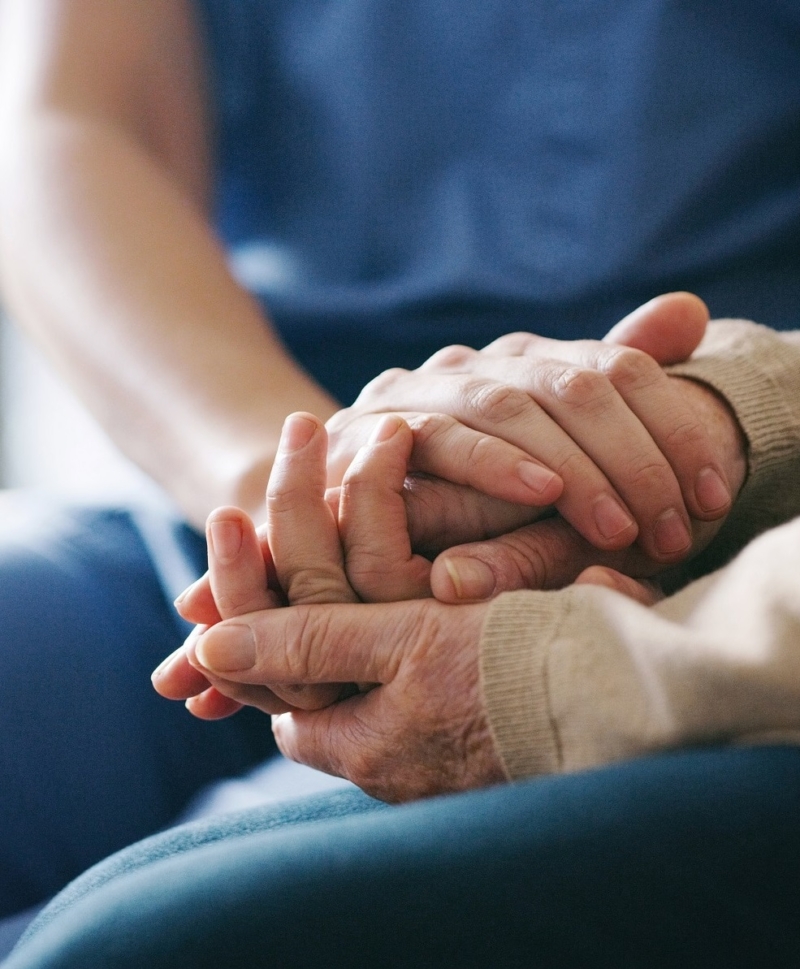 Carer holding patient hand.